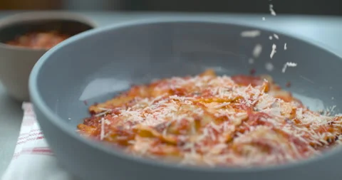 Parmesan cheese being grated onto tomato ravioli dish in bowl in ultra slow moti Stock Footage 199455891