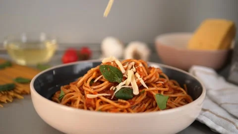 Parmesan cheese falling over steaming pasta, richly draped in vibrant tomato Stock Footage 302840063