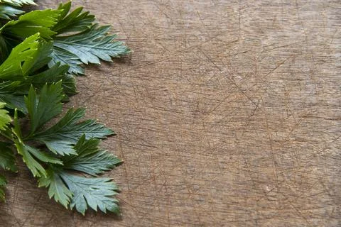 Parsley leaf forming side frame on scratched wooden background Foto stock