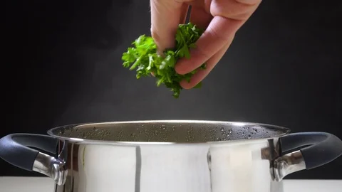 Parsley is put in pan. The cook is preparing soup. The pan is on the stove. From Stock Footage 89840678