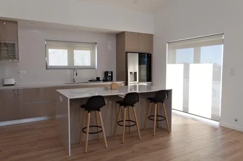 Part of big beige kitchen with table with high black wood chairs Stock-Fotos