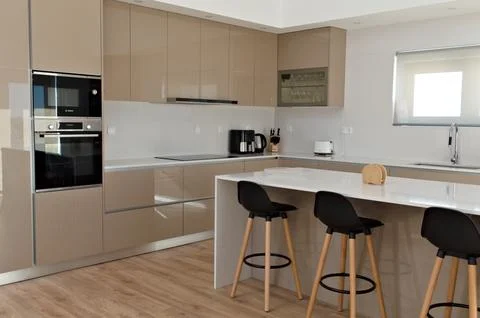 Part of big beige kitchen with table with high black wood chairs Stock Photos