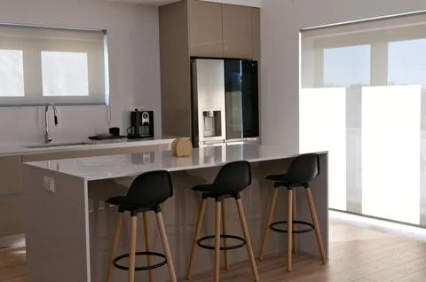 Part of big beige kitchen with table with high black wood chairs Foto stock