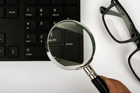 Part of a black computer keyboard, a magnifier and eyeglasses isolated on a whit Stock Photos