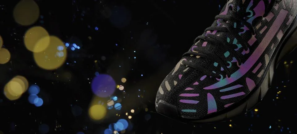 Part of a black sneaker with reflective elements on a black background with b Fotos Stock