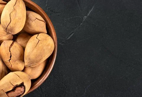 Part of a bowl with in-shell pecans on an empty dark background under the tex Stockfoto's
