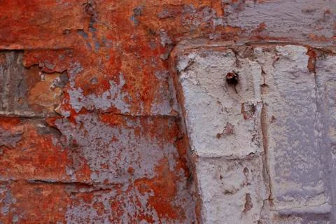 Part of a brick wall with peeling white, gray and red paint Stock Photos
