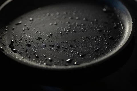 Part of empty cast iron pan of black color with drops of vegetable oil. Close-up Stock-Fotos