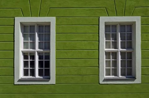 Part of facade of old building with two windows on green wall is located on o Stock Photos