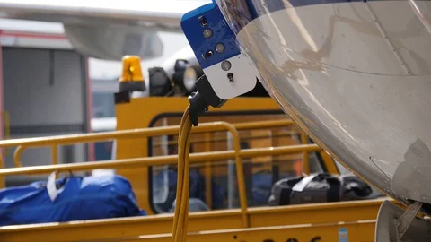 Part of fuselage with ground power wire. Bags move out the plane on belt loader 库存影片 94543334