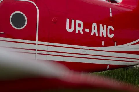 Part of the gleaming hull of a red UR ANC small passenger plane in sunset light Stock Photos