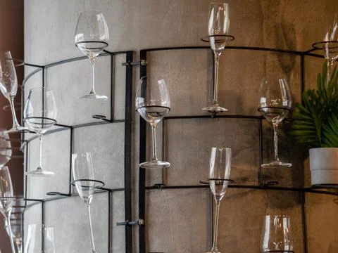 Part of a gray column with a rack of glasses and flowers Stock Photos
