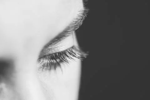 Part of human face with look down in black background. BW photo. Stock Photos