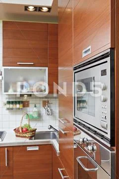 Part of kitchen interior with wooden furniture and build in microwave oven Stock Photos