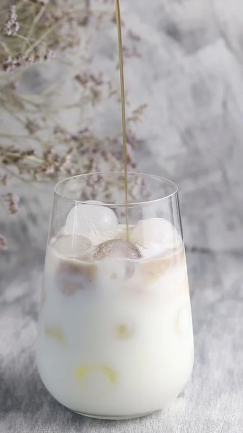 Part of making iced coffee. Coffee is poured into milk. Vertical video 動画素材 160815182