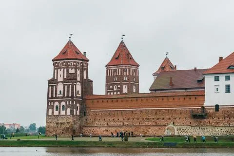 Part of the Mir Castle complex on the lake in cloudy weather. Stock Photos