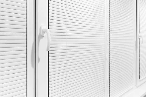 Part of a modern plastic window with closed white horizontal blinds Stock Photos