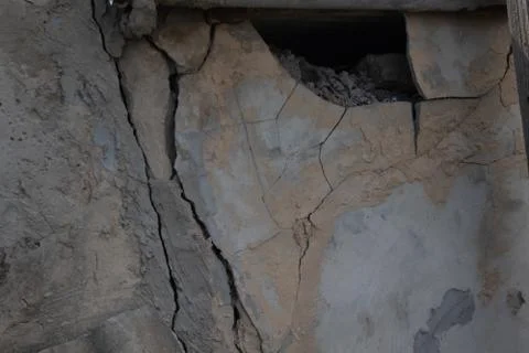 Part of the old collapsing wall with cracks and loose plaster pieces close up Stock Photos