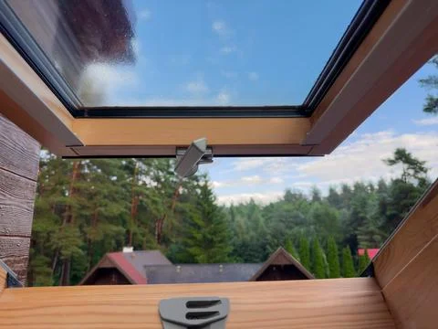 Part of open roof window, view to roofs and forest Stock Photos