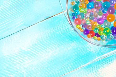 Part of the plate with multi-colored hydrogel balls on a wooden Stock Photos