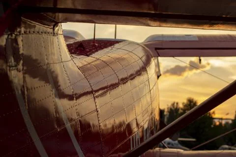 Part of the shiny hull of a red small-passenger plane in sunset light Stock Photos