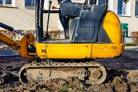 Part of a small crawler excavator standing in the mud. Cab and tracks. Stock Photos