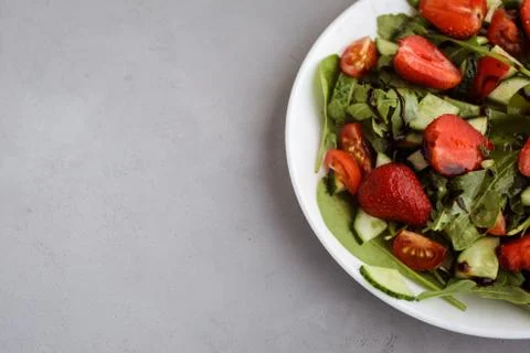 Part of strawberry salad with spinach and balsamic sauce on the grey background Stock Photos