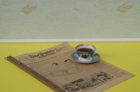 A part of a tea set and reading glasses on a newspaper Stock Photos