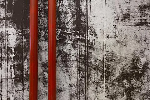 Part view of two red pipes on the shabby painted concrete wall background Stock Photos