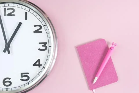 Part of wall clock with pink notepad and pen Stock Photos