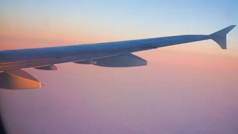 Part of the wing of an airplane through a window against a blue evening sky.. Stock Footage 73654703