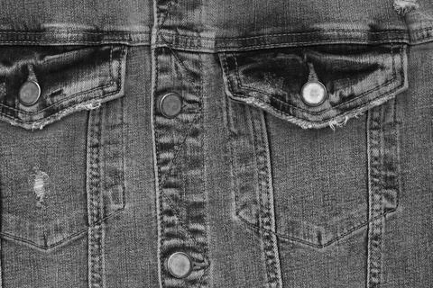 Part of a worn denim jacket made of black fabric closeup Stock Photos