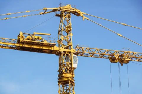 Part of yellow construction tower crane arm against blue sky Stock Photos