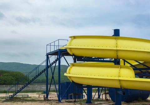 Part of a yellow waterslide on the beach Stock Photos