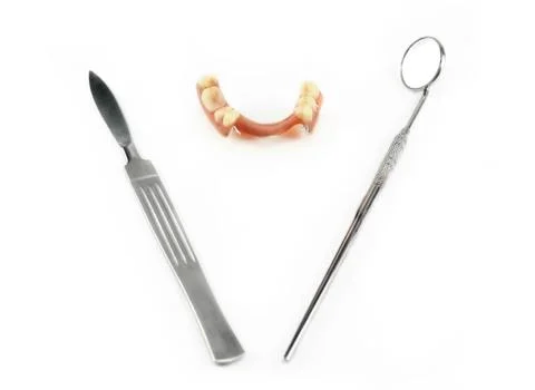 Partial denture between scalpel and dental mirror Stock Photos