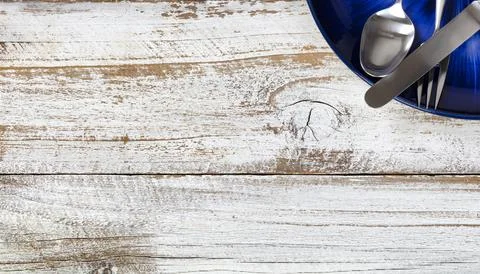 Partial dinner table setting with cutlery and dark blue plate on white rust.. Stock Photos