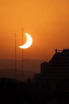 Partial eclipse sun descending behind antenna masts Stock Photos