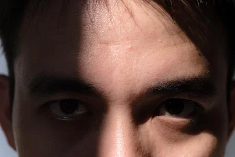 The partial face of a man covered in shadow and sunlight Foto stock