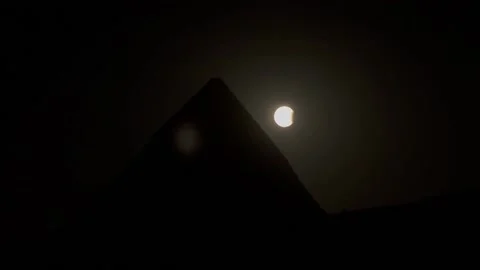 Partial lunar eclipse appears behind pyramids of Giza in Egypt, El Cairo (es-ES) Stock Footage 284913360