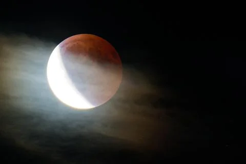 Partial lunar eclipse with bright and dark moon phases in night sky Stock Photos