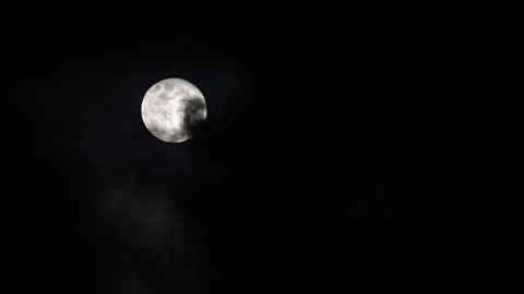 Partial lunar eclipse hiding behind clouds at night Stock Footage 302237819