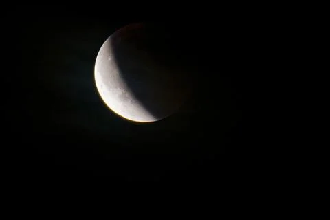 Partial lunar eclipse with shadow covering half of the moon in dark night sky Stock Photos