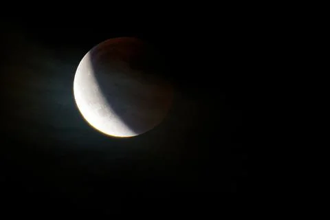 Partial lunar eclipse with shadow covering half of the moon in dark night sky Stock Photos