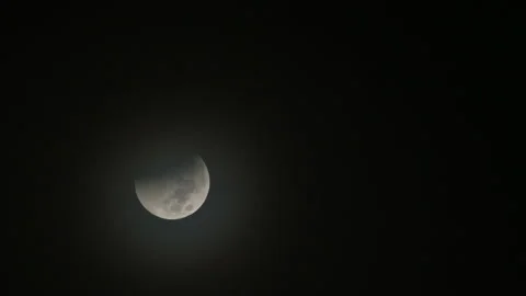 Partial Lunar Eclipse with Shadow Starting to Appear and Clouds Rolling Stock Footage 222705993