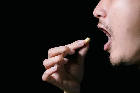 A partial man's face who is going to consume a yellow pill Stock Photos