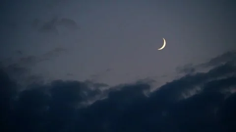 A partial moon and fast-moving clouds at dusk. Stock Footage 346532060