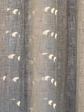 The partial phases of a solar eclipse projected as crescent shapes on a lin.. 스톡 사진