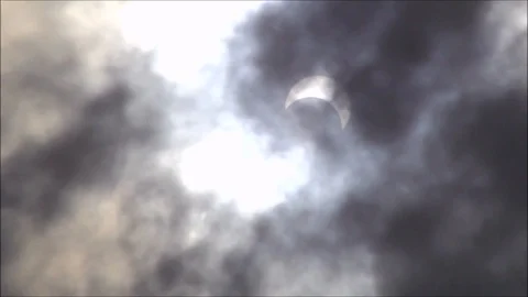 Partial solar eclipse and passing dark rain clouds Stock Footage 121905474