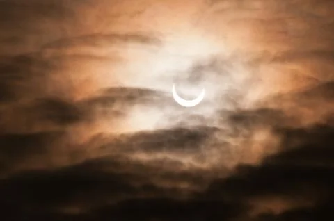 Partial solar eclipse behind clouds morning sky Foto stock