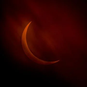 Partial solar eclipse as clouds move by orange crescent sun Stock Photos